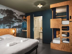 Moderni hotellihuone, jossa on suuri sänky, puinen kerrossänky, kylpyhuone, jossa on pesuallas ja peili, sekä seinällä oleva suuri seinämaalaus, jossa on kuvattuna puita.