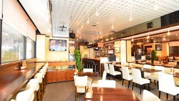 A restaurant with a bar area, multiple seating options including booths and tables, and a ceiling with a grid pattern.