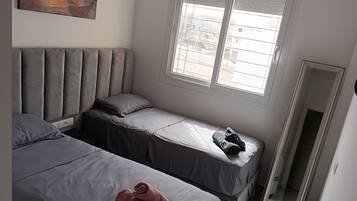 Une chambre avec deux lits, une grande fenêtre et un tableau au mur.