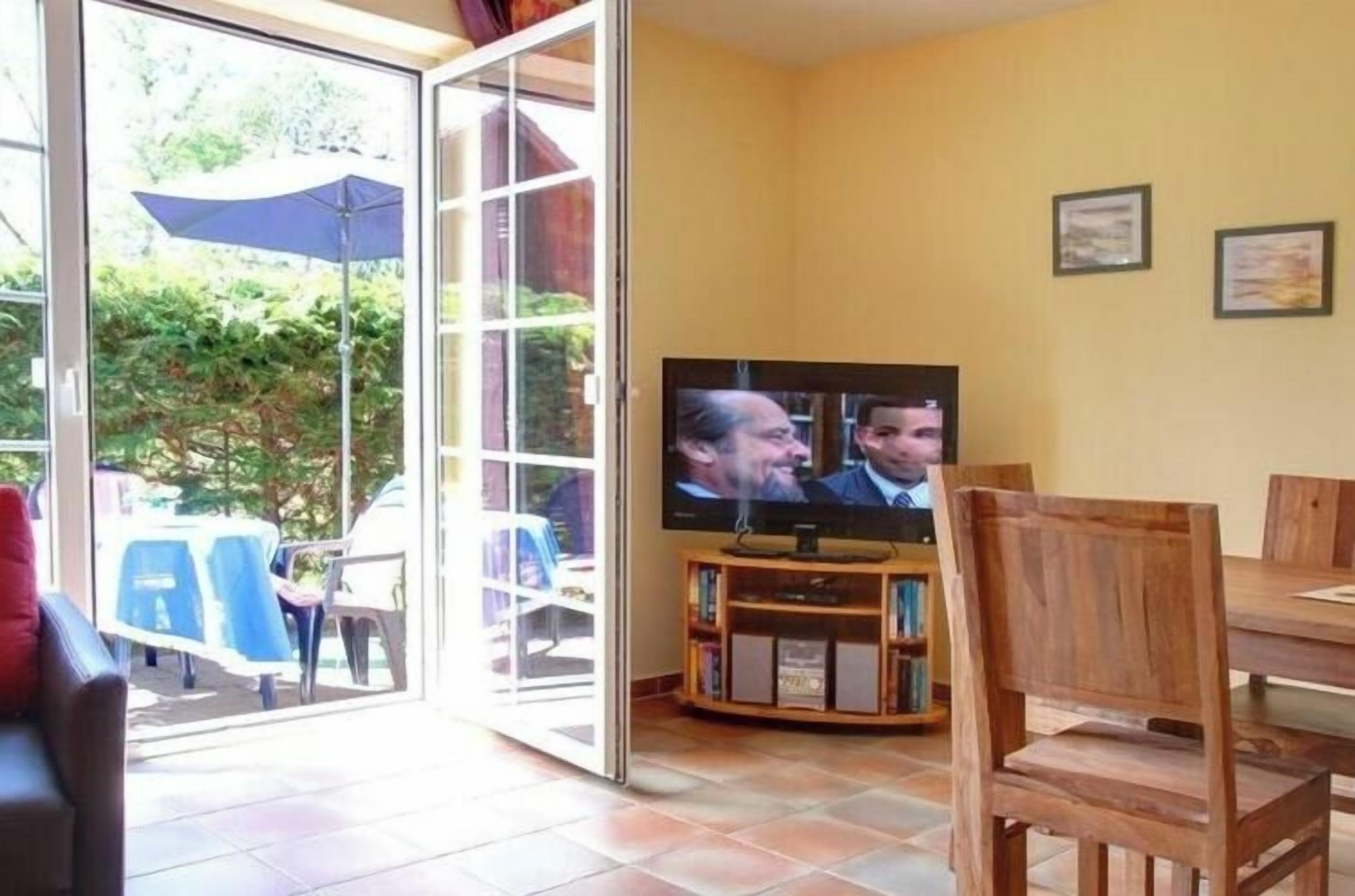 A living room with a television, a wooden chair, and a dining table.