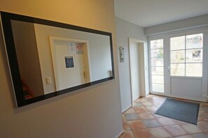 Ein Flur mit einer Tür, einem Spiegel und einem Fenster.