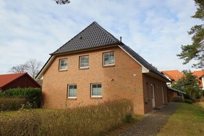 Ein einstöckiges Backsteinhhaus mit geneigtem Dach, einer Haustür und einer kleinen Veranda.