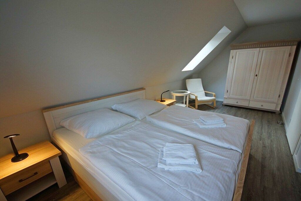 Een slaapkamer met een groot bed, een nachtkastje, een stoel en een kledingkast.