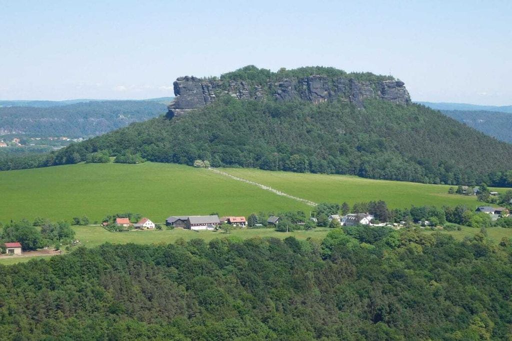 A rural landscape with a prominent rock formation and scattered houses.