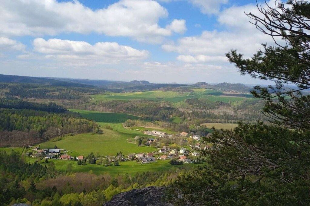 A rural landscape with a village, green fields, and a clear sky.