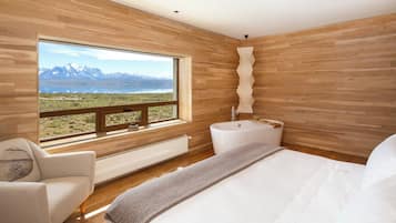 Un dormitorio con un ventanal grande, una bañera y vistas a las montañas.
