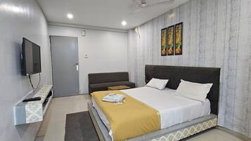 A hotel room with a bed, a sofa, a television, and a painting on the wall.