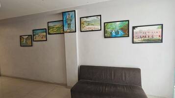 Un área de recepción con un sofá, dispensador de agua y una pared con fotografías enmarcadas.