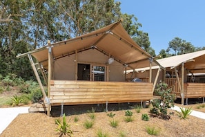 A wooden structure with a covered patio area, surrounded by a landscaped garden with various plants. - Reflections Holiday Parks Jimmys Beach (Hawks Nest)