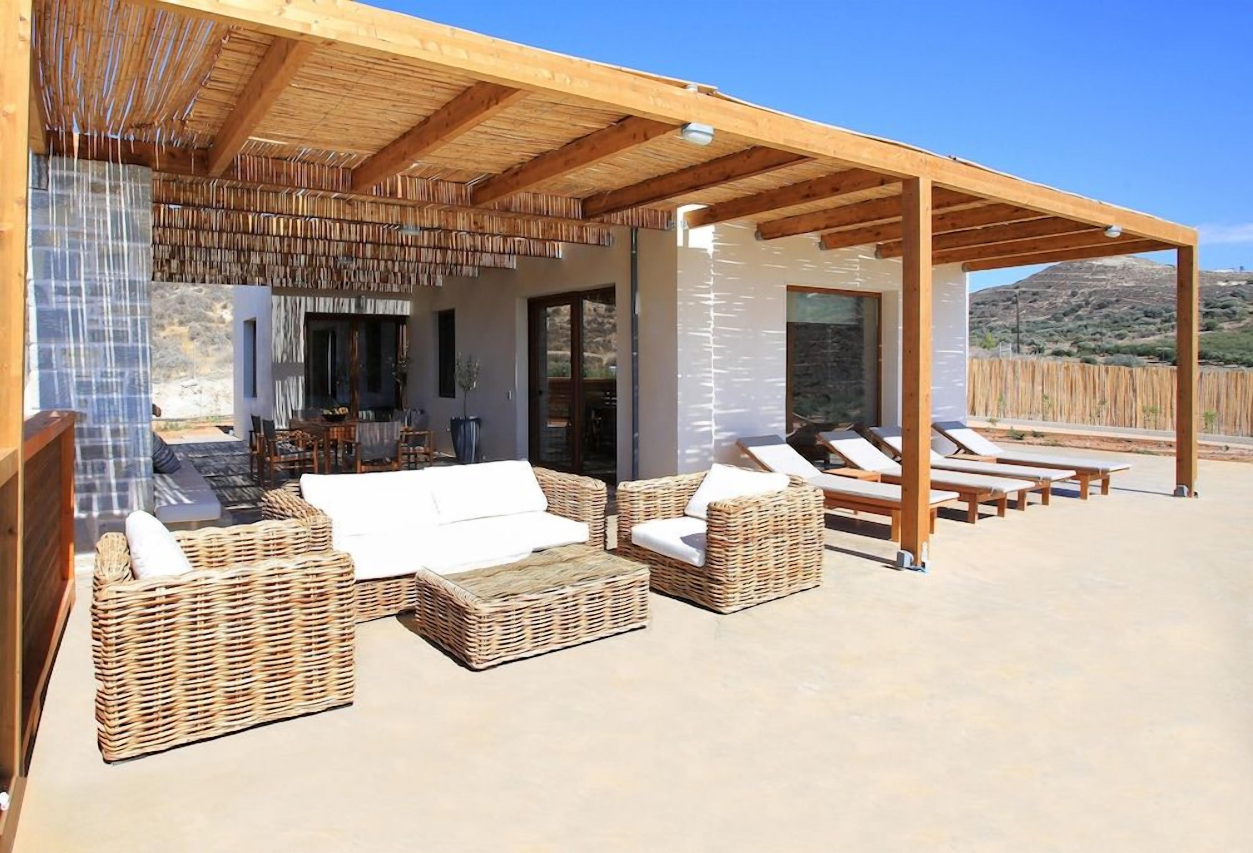 An outdoor patio with wicker furniture, a covered area, and a view of the landscape.