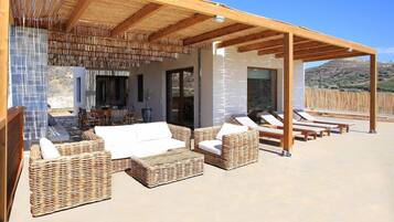 An outdoor patio with wicker furniture, a covered area, and a view of the landscape.