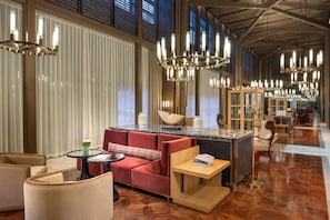Un hall d’hôtel moderne avec un canapé rouge, une petite table ronde et un coin bar.