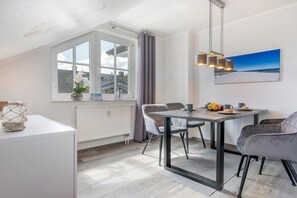 Een moderne eetruimte met een tafel, stoelen en uitzicht op het omliggende landschap door een raam.
