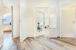 A modern interior with a wooden floor, white walls, and a glass door leading to a balcony. - Granitz Residential Park 26 Sandschloss (Ostseebad Binz)