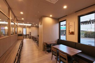 Interior de restaurante con mesas y bancos de madera, un ventanal con vistas y un reloj en la pared.