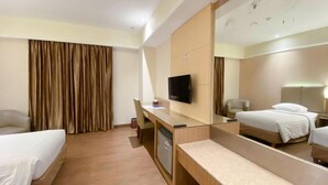 Una habitación de hotel con cama, escritorio, silla, televisor y un espejo grande.