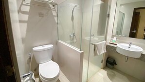 Un baño moderno con inodoro, cabina de ducha de vidrio y lavamanos.