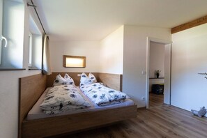 Ein Schlafzimmer mit einem hölzernen Bett, einem Nachttisch und einem kleinen Fenster.