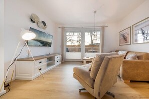 Una sala de estar moderna con un sofá, una mesa de centro, una lámpara y obras de arte en las paredes.