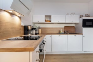 A modern kitchen with white cabinetry, a wooden countertop, and a built-in stove. - Villa Düne 4 Summer retreat (Ostseebad Binz)