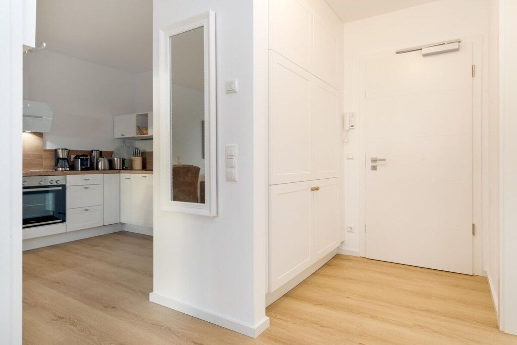A modern kitchen with white cabinets and a built-in oven.