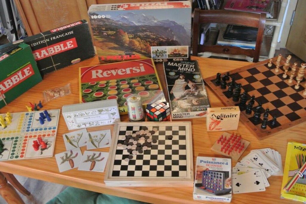 Une table sur laquelle on trouve divers jeux de société, notamment Scrabble, Reversi et Master Mind.