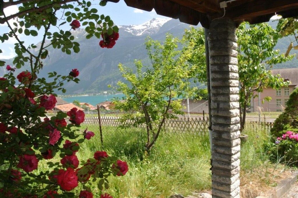 Un jardin avec des roses rouges, un pilier de pierre et une vue sur la montagne.
