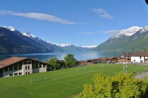 Ein Wohngebiet mit einer grünen Wiese, Häusern und Bergen im Hintergrund.