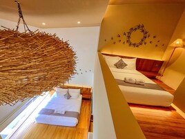 Un dormitorio moderno con un candelabro colgante de bambú, una cama con ropa blanca, un cabecero de madera y una decoración de aves en la pared.
