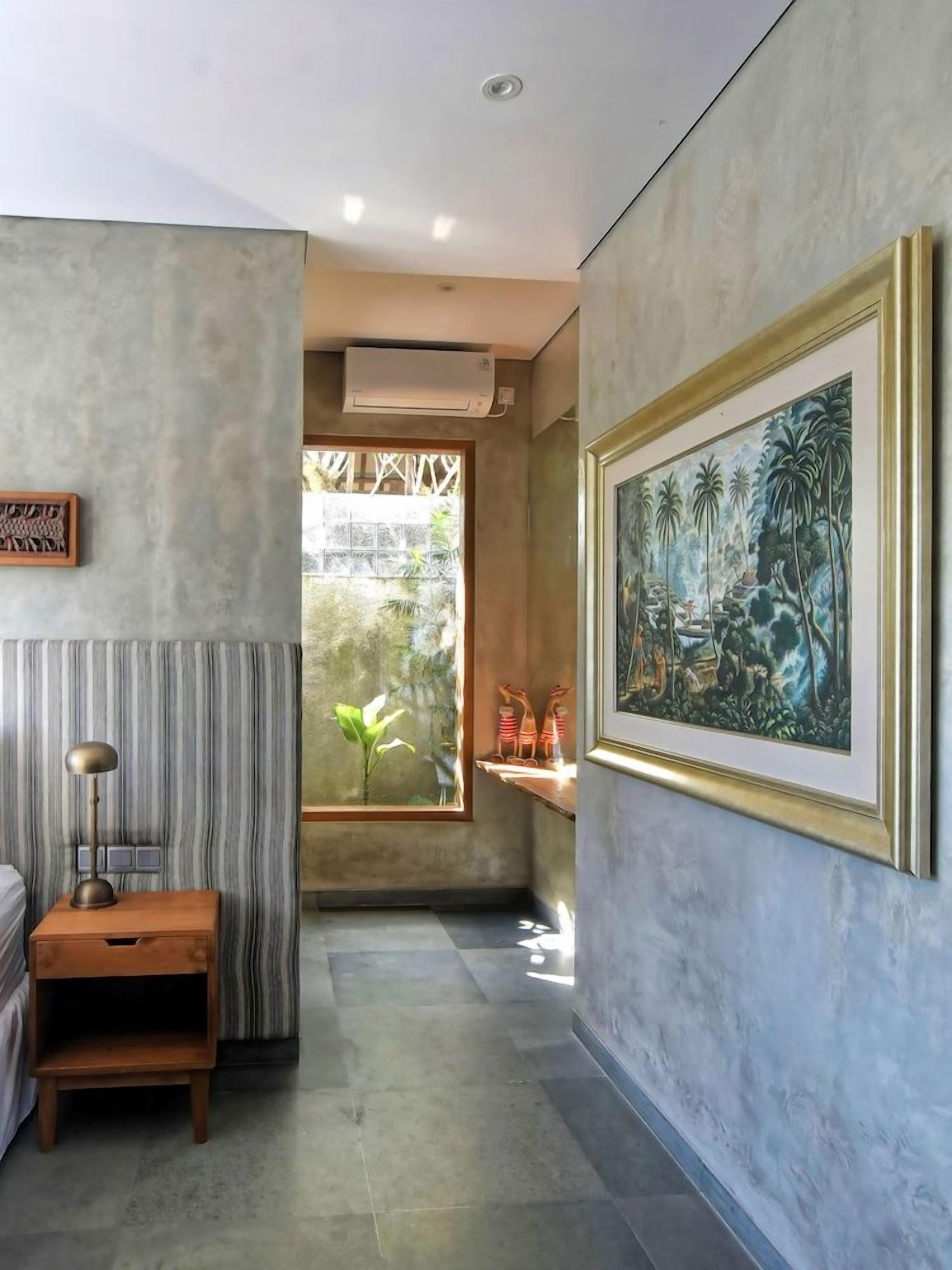 A modern interior with a large window, a framed painting, and a small wooden table.