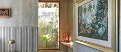 Un interior moderno con un ventanal grande, un cuadro enmarcado y una pequeña mesa de madera.