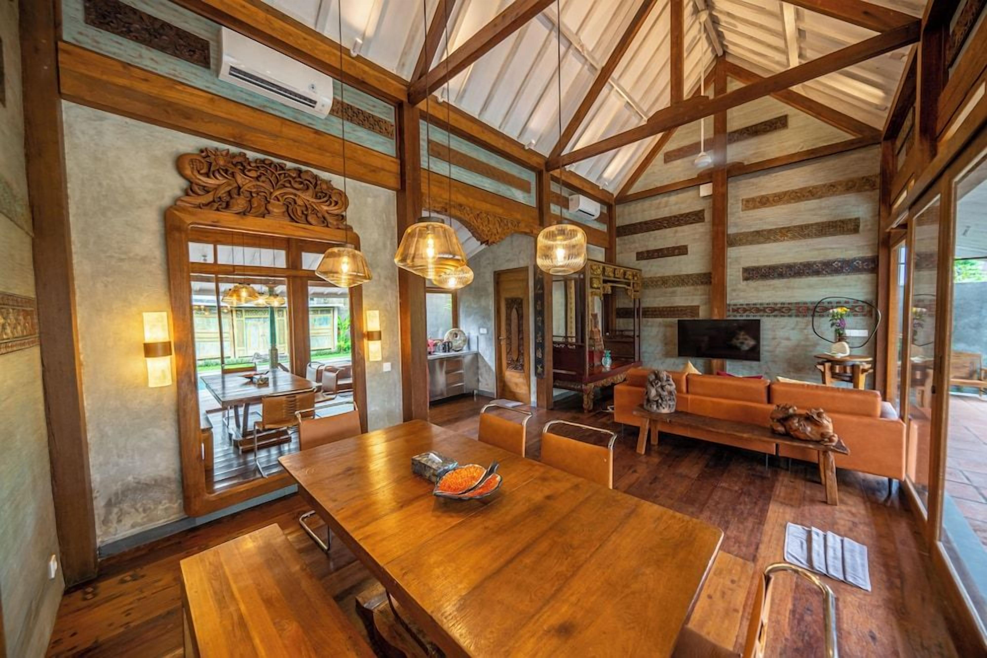 A spacious dining area with a long wooden table, multiple chairs, and hanging pendant lights.