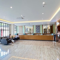Un hall de hotel con mostrador de recepción, zona de estar y grandes ventanales.