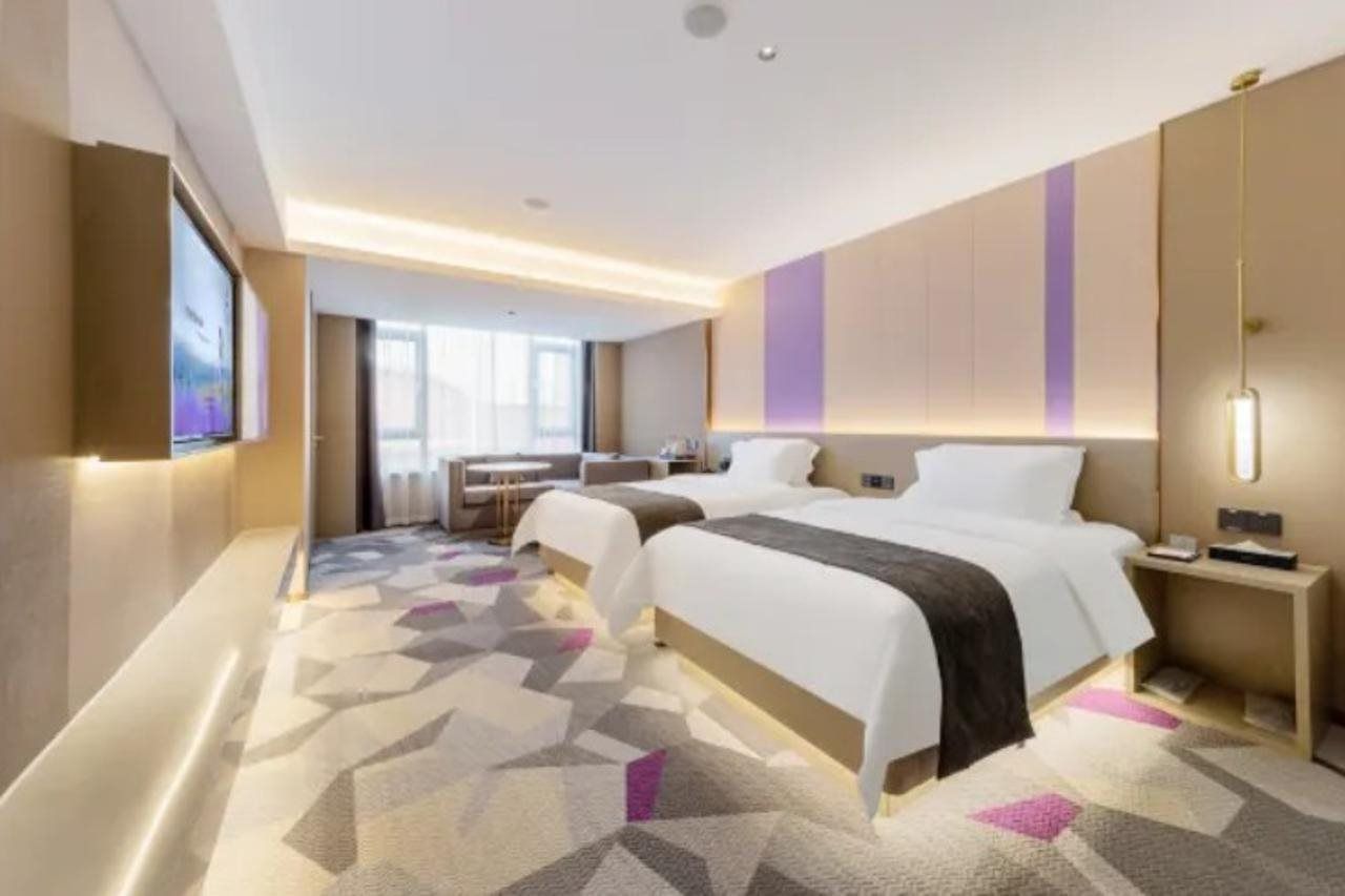 Quarto de hotel com duas camas, uma escrivaninha e televisão.