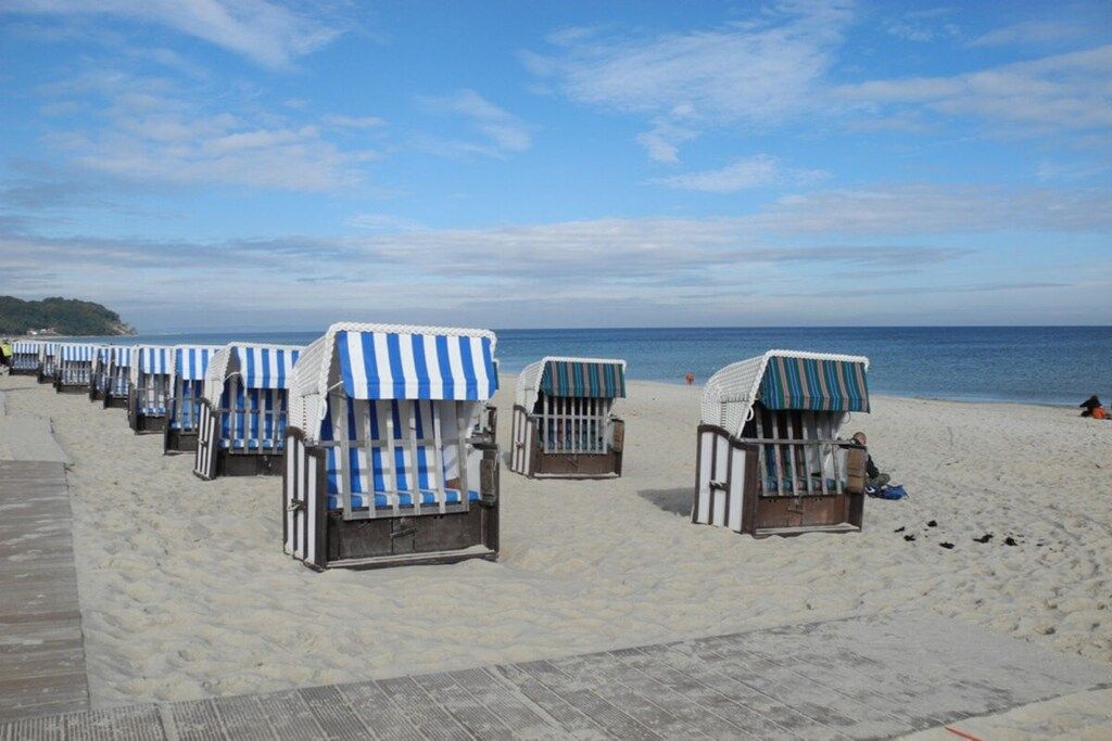 A row of beach chairs with striped awnings on a sandy beach.