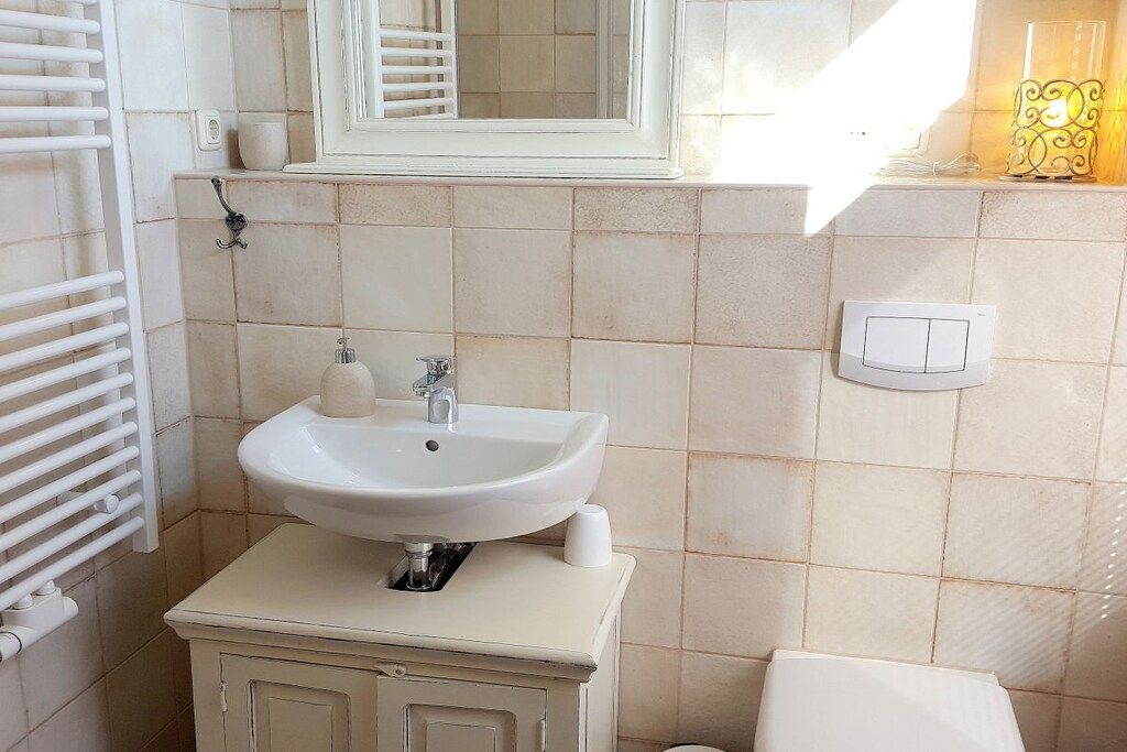 A bathroom with a white sink, a mirror, a towel rack, and a light fixture.