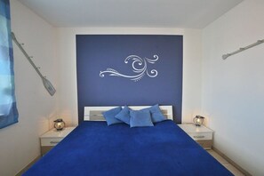 Een slaapkamer met een groot bed, twee nachtkastjes en een decoratief wandobject.