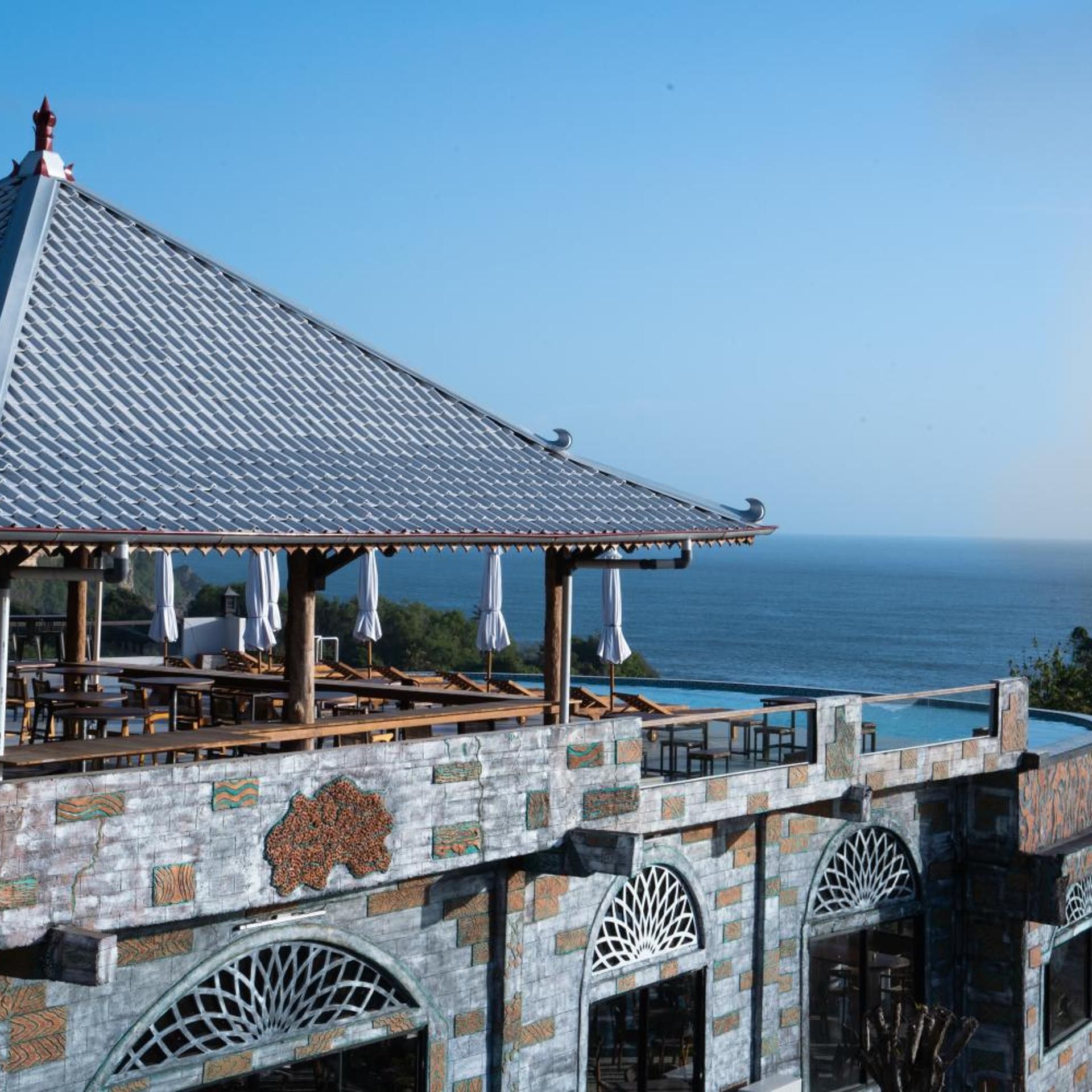 A rooftop terrace with a view of the ocean, featuring a covered seating area and a swimming pool.
