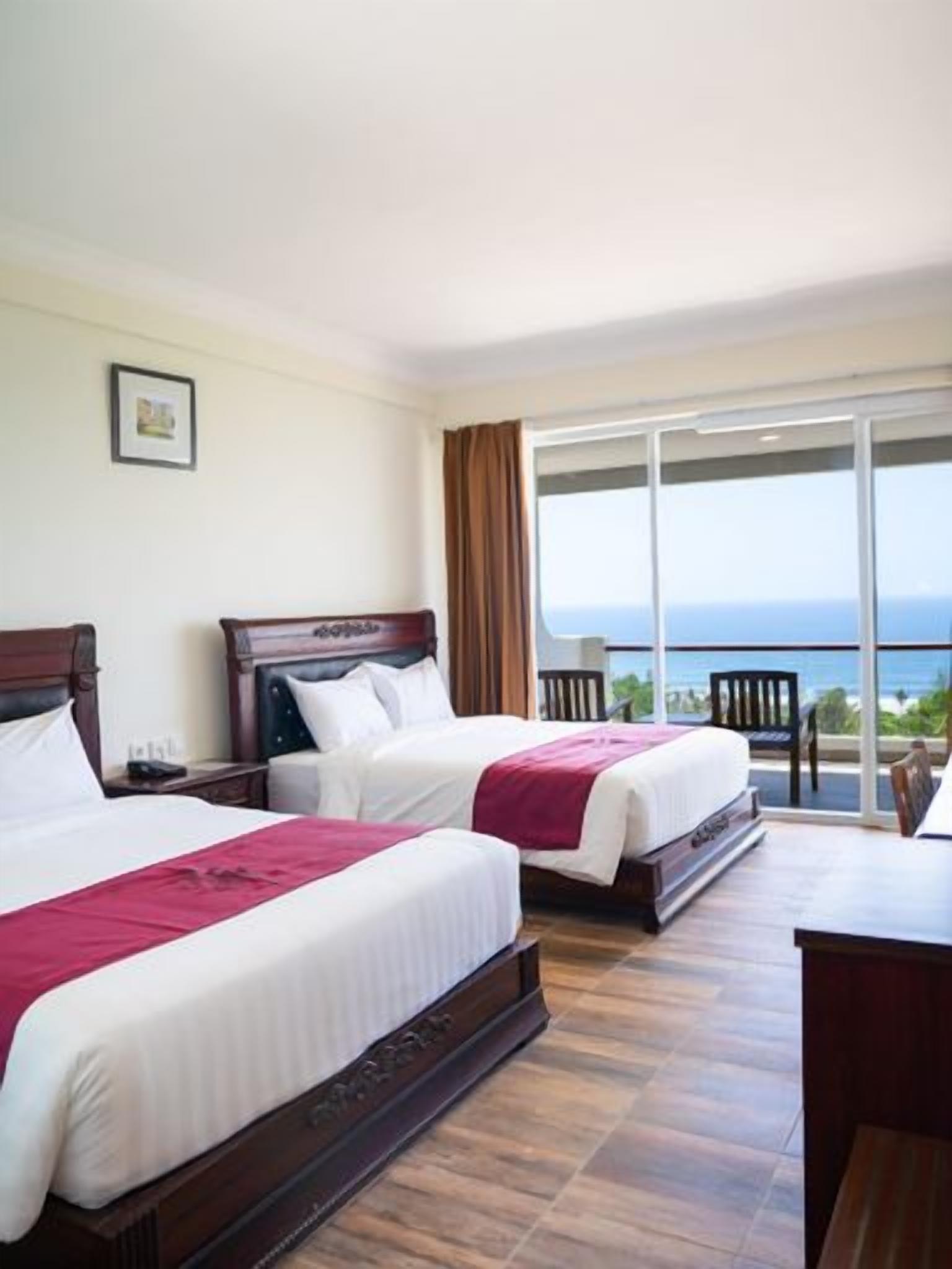 A hotel room with two beds, a large window, and a balcony.