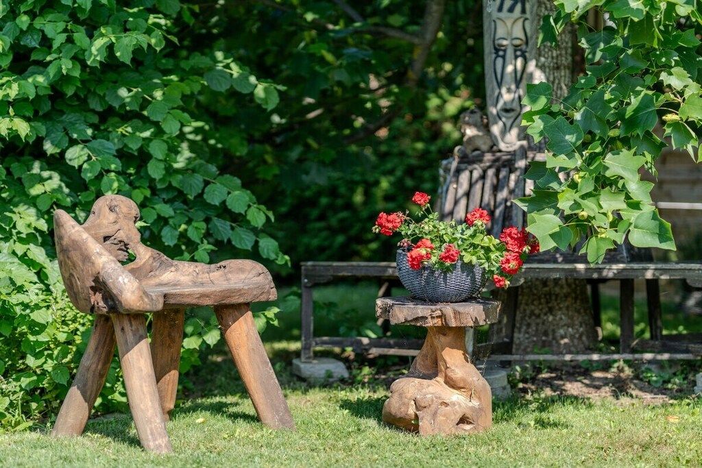 Ein rustikaler Sitzbereich im Freien mit einer Holzbank und einem kleinen Tisch mit einem Blumentopf.