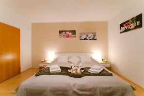 A hotel room with a bed, two bedside tables, a nightstand, a wooden headboard, and wall-mounted pictures. - Holiday home with 1 bedroom (8344 Bad Gleichenberg)