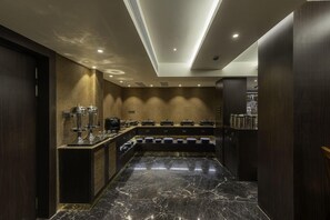 A modern kitchen with marble countertops, a built-in stove, and a coffee machine.