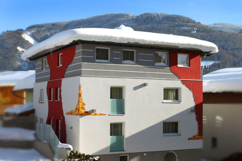 Ein mehrgeschossiges Gebäude mit verschneitem Dach, Fenstern und einer Tür.