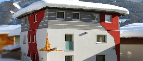 A multi-story building with a snow-covered roof, windows, and a door.