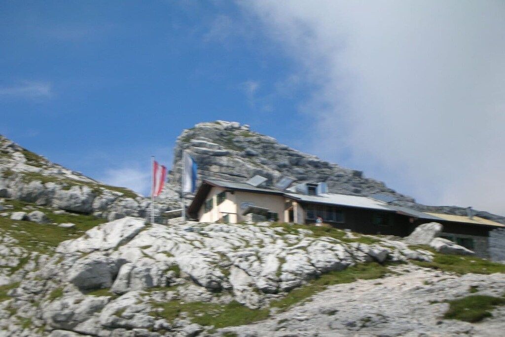 A mountain lodge with a rocky terrain, a flag, and a clear sky.
