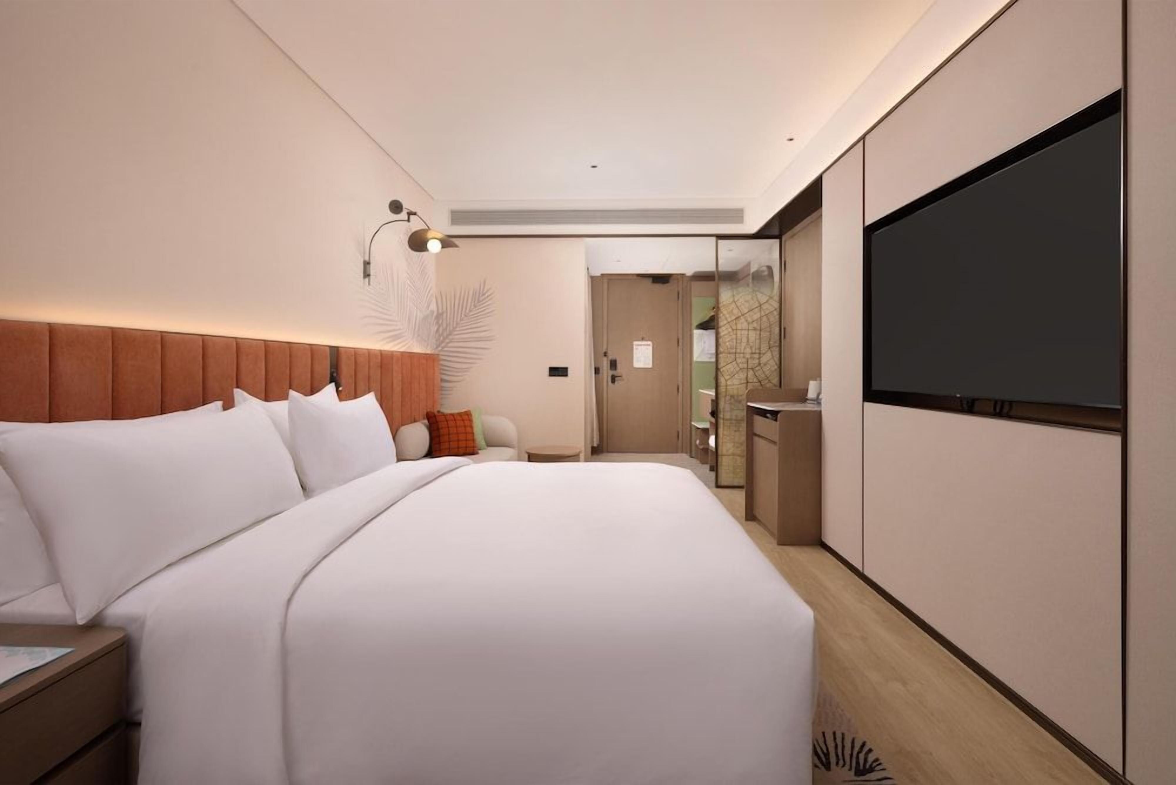 Une chambre d’hôtel moderne avec un grand lit, un téléviseur à écran plat, une table de chevet et une petite table.