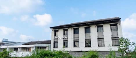 A building with the name 'MOANA' on its facade, surrounded by greenery.