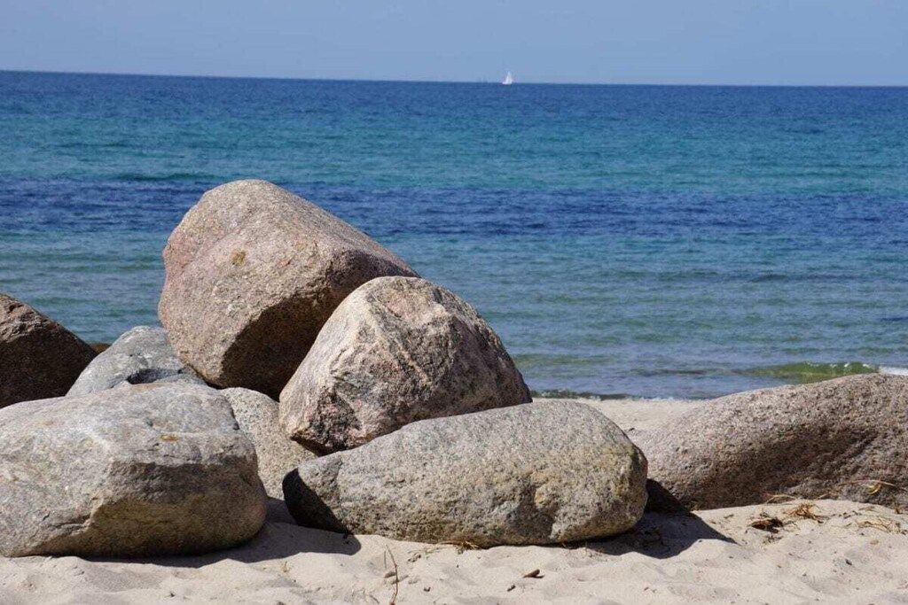 A beach with large rocks and a clear view of the ocean.