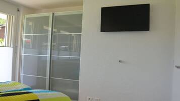 Ein Schlafzimmer mit einem Bett, einer Schiebetür aus Glas und einem angebrachten Fernseher.