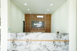 A reception area with a marble counter, wooden panel wall, and a sign that reads 'bobbi in'.